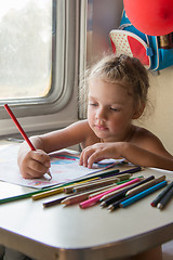 Image showing Four-year girl drawing with pencils at a table in a train