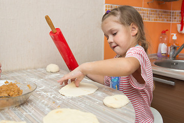 Image showing The girl rolls the dough with a rolling pin for pies