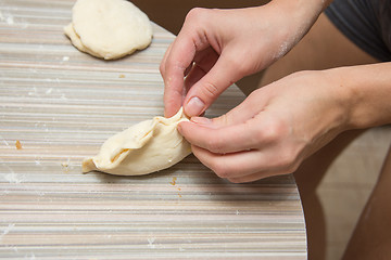 Image showing Female hands fasten the seam pie on the kitchen table