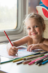 Image showing Four-year girl draws pencil drawing of a table in a second-class train carriage