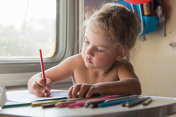 Image showing Carried away by the girl draws pencils at the table in a train