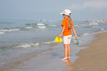 Image showing Girl standing on the beach with a bucket and slaps hands