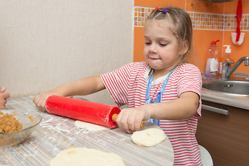 Image showing Girl hard rolls rolling pin pancake dough for pies