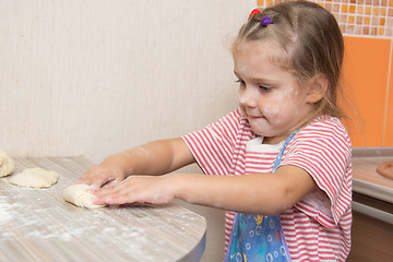 Image showing Girl sculpts cakes at the kitchen table