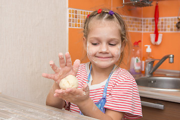 Image showing Happy little girl girl sculpts a pie at the kitchen table