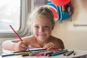 Image showing Happy little girl drawing with pencils at a table in a train