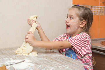 Image showing Cheerful girl tears off a piece of dough