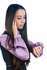 Image showing Attractive woman talks on phone and looks on watch