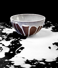 Image showing Ceramic bowl and spilled milk in black