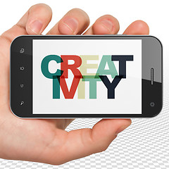 Image showing Advertising concept: Hand Holding Smartphone with Creativity on 