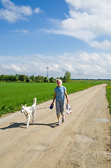 Image showing Woman with a dog goes on a country road  