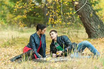 Image showing Young romantic couple sits on plaid. Autumn picnic