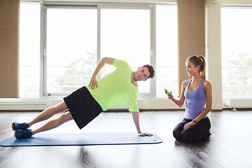 Image showing man and woman doing plank exercise on mat in gym