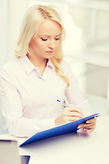 Image showing smiling businesswoman with clipboard in office