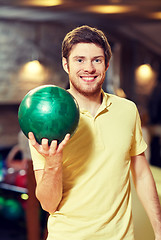 Image showing happy young man holding ball in bowling club