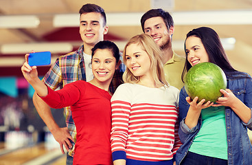 Image showing happy friends with smartphone in bowling club