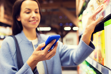 Image showing happy young woman with smartphone in market