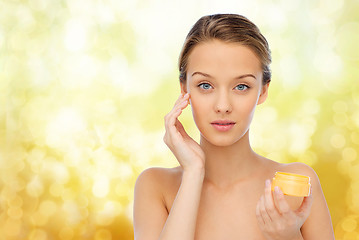 Image showing young woman appying cream to her face