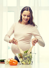 Image showing happy pregnant woman preparing food at home