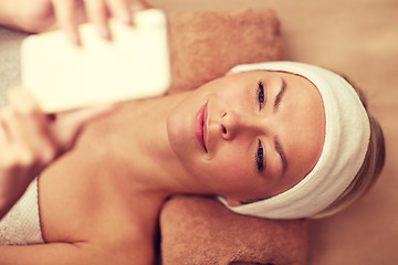 Image showing close up of smiling woman with smartphone in spa