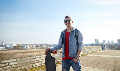 Image showing smiling teenager with longboard on street