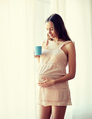 Image showing happy pregnant woman with cup drinking tea at home