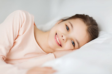 Image showing happy smiling girl lying awake in bed at home