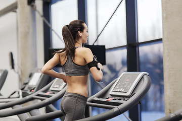 Image showing woman with earphones exercising on treadmill