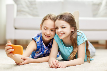 Image showing happy girls with smartphone taking selfie at home