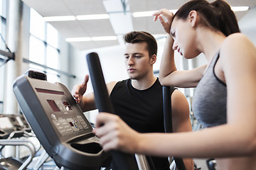 Image showing woman with trainer exercising on stepper in gym