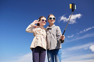 Image showing happy girls with smartphone selfie stick