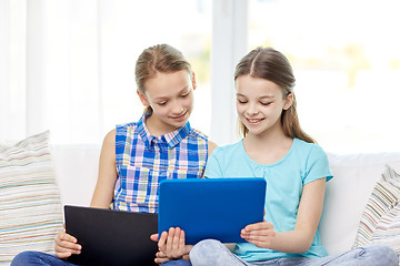 Image showing happy girls with tablet pc sitting on sofa at home