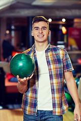 Image showing happy young man holding ball in bowling club