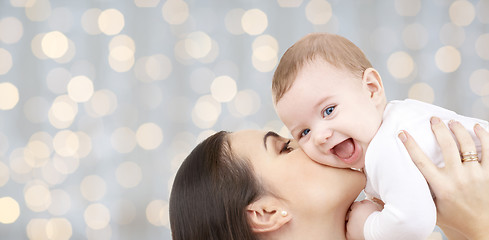 Image showing happy mother kissing her baby over lights