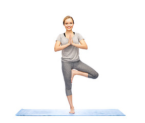 Image showing woman making yoga in tree pose on mat