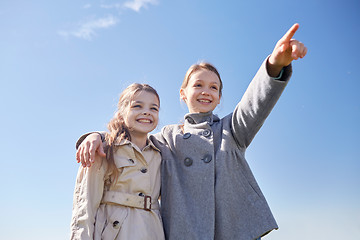 Image showing happy little girls hugging and pointing finger