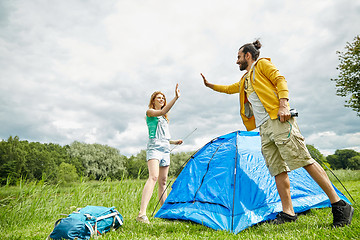 Image showing happy couple setting up tent outdoors