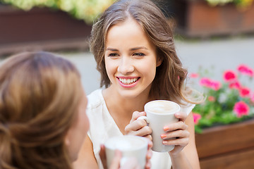 Image showing smiling young women with coffee cups at cafe