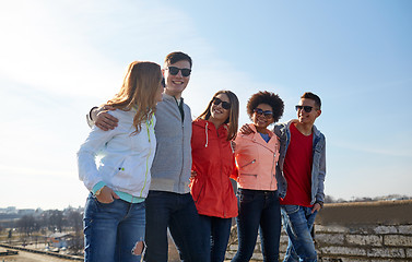 Image showing happy teenage friends walking along city street