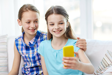 Image showing happy girls with smartphone taking selfie at home