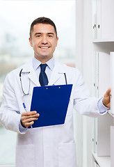 Image showing happy doctor with clipboard in medical office