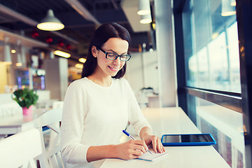 Image showing smiling woman with tablet pc at cafe