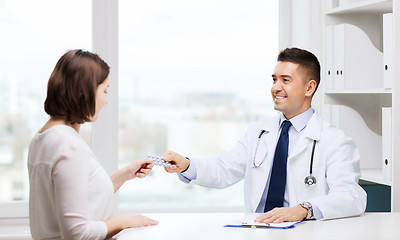 Image showing smiling doctor giving pills to woman at hospital