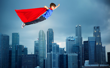 Image showing boy in red superhero cape flying over city