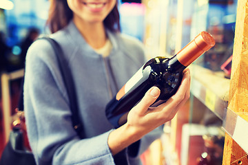 Image showing happy woman choosing and buying wine in market