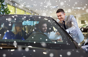 Image showing happy couple with car dealer in auto show or salon