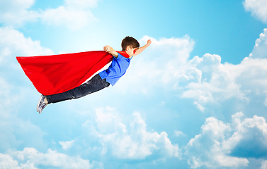 Image showing boy in red superhero cape and mask flying over sky