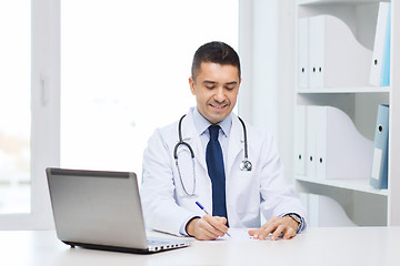 Image showing smiling male doctor with laptop in medical office