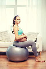 Image showing happy pregnant woman exercising on fitball at home