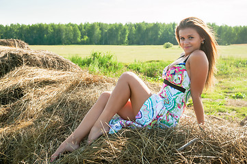 Image showing Young blond woman sits on hay